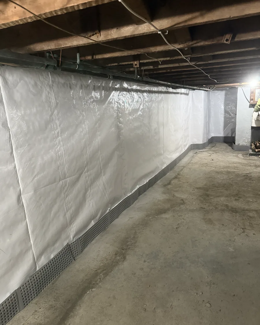 White wall vapor barrier terminated into the perimeter drainage track along a basement wall