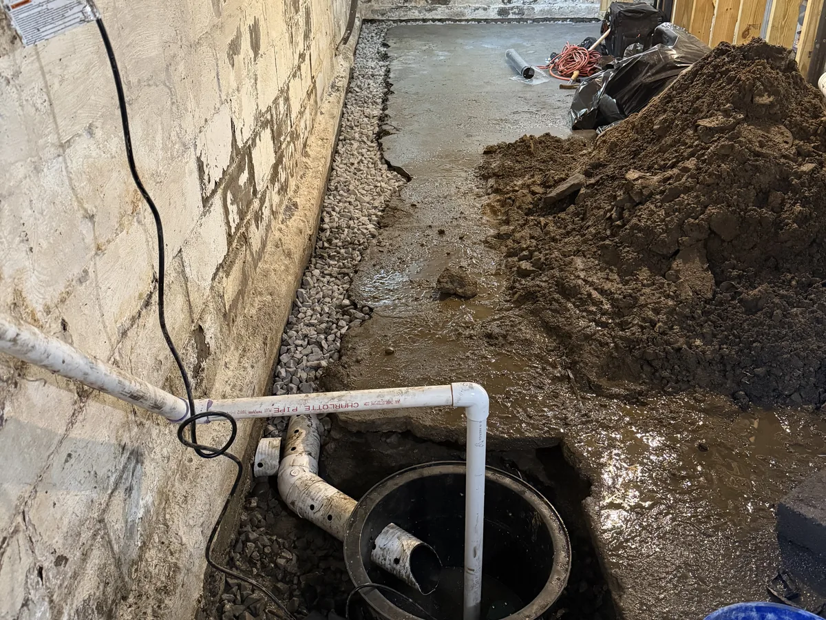 Interior perimeter trench open, with washed stone, perforated pipe and the sump basin being set